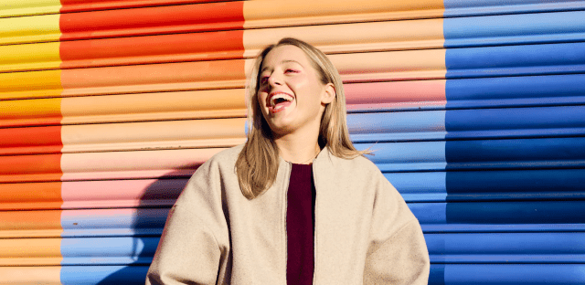 A student laughing joyfully against a painted wall