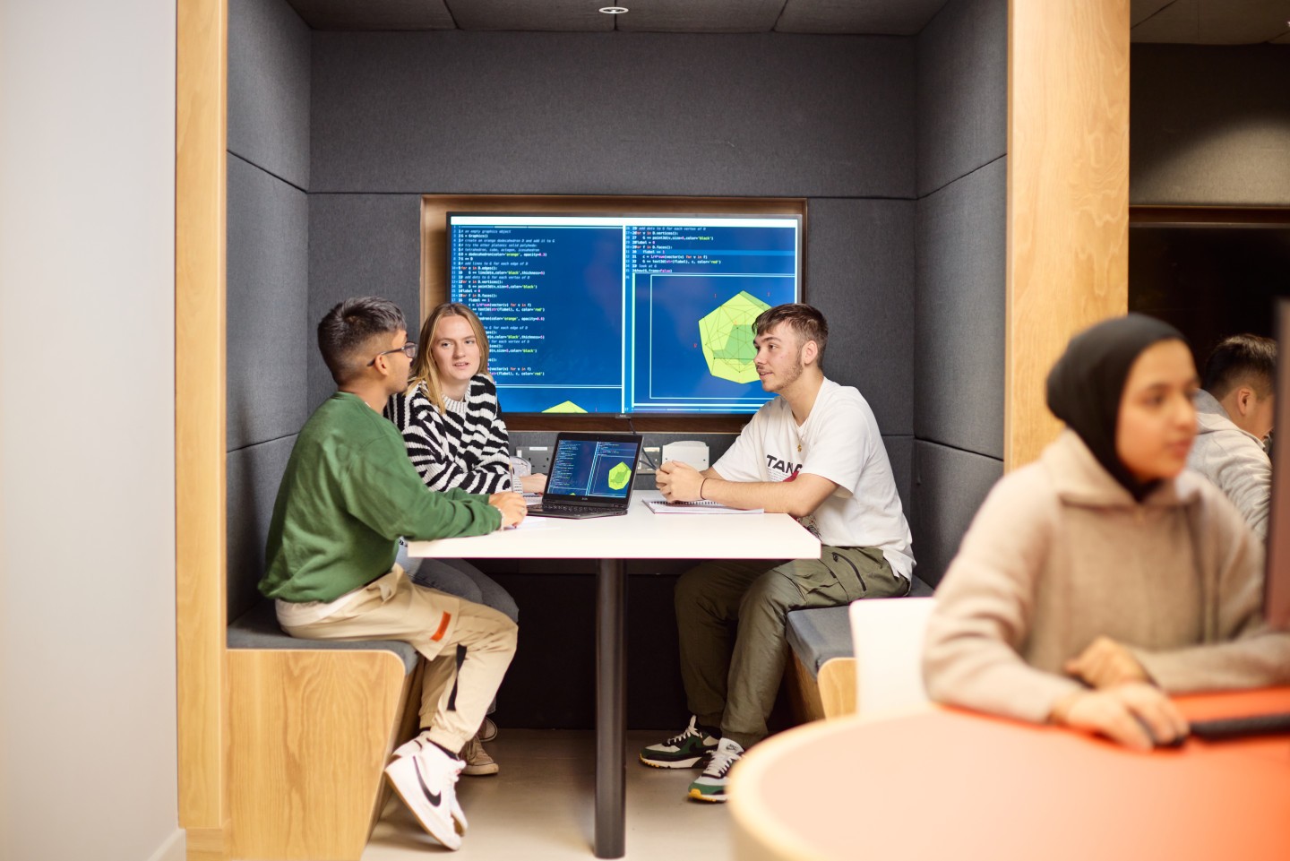 students sat at a table in a booth in the new computing studio