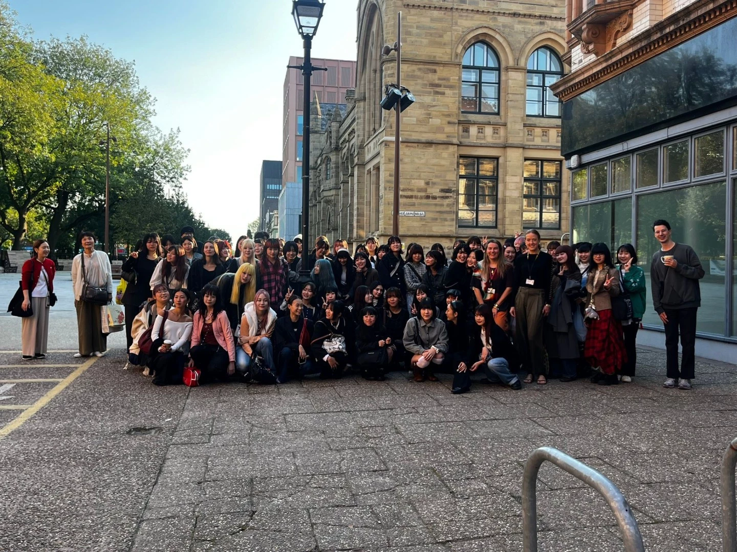 Image of a number of staff and students from the fashion show stood outside Manchester Fashion Institute