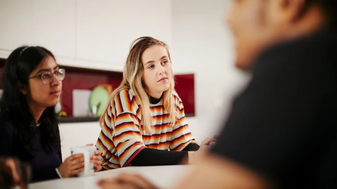 Three students talking around a table in Manchester Met accommodation