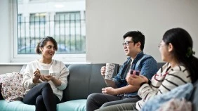 Students drinking coffee on sofas in halls of residence shared area