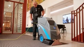 A cleaner vacuuming a building entrance