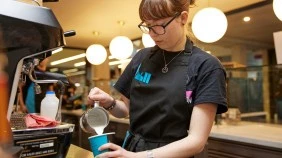 A barista preparing a coffee in a campus cafe