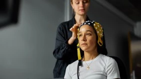 Psychology student adjusting a head ECG mask on another person sitting in a clinical environment